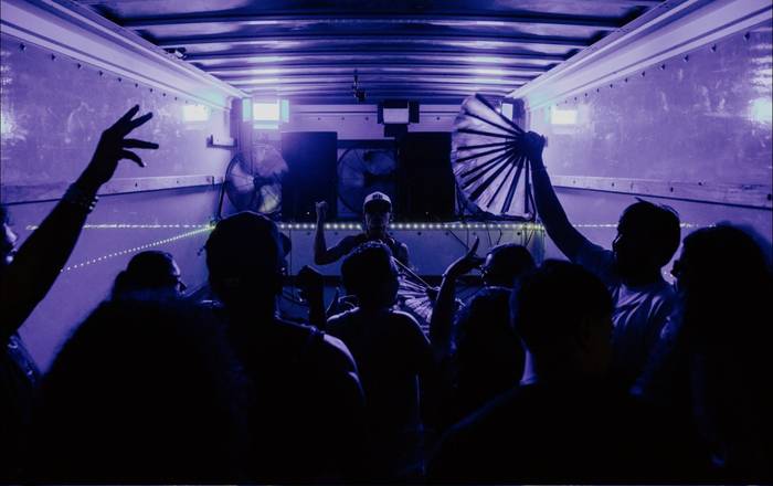 Silhouettes and a folding fan held high, the whole truck washed purple